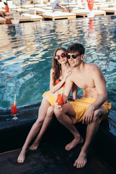 Happy Young Woman Hugging Handsome Boyfriend While Sitting Poolside Together — Stock Photo, Image