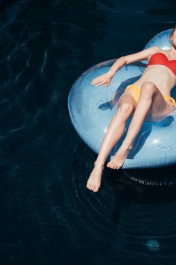 yüzme havuzunda yüzme halkası üzerinde güneşlenme mayo genç kadın kırpılmış görünümü