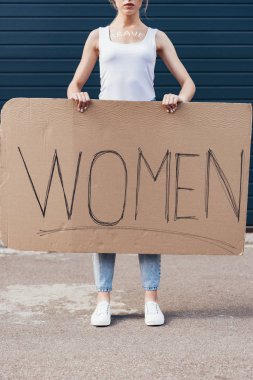 cropped view of feminist with word brave on body holding placard with inscription women on street clipart