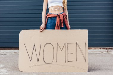 cropped view of feminist with inscription power on belly holding placard with slogan women on street clipart