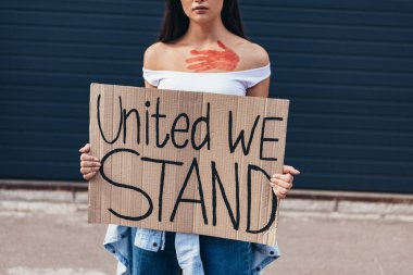 cropped view of feminist holding placard with inscription united we stand on street clipart
