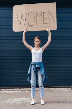 full length view of feminist holding placard with inscription women on street clipart