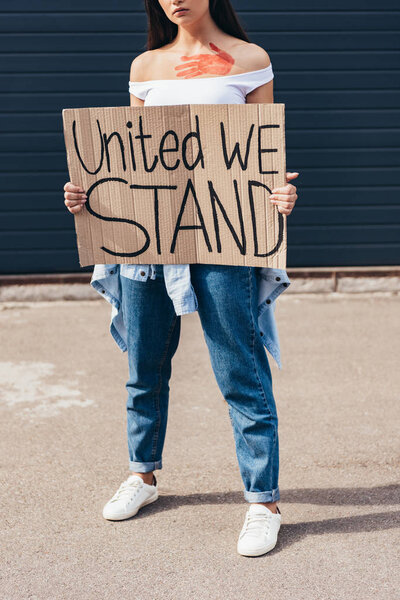 cropped view of feminist holding placard with inscription united we stand on street