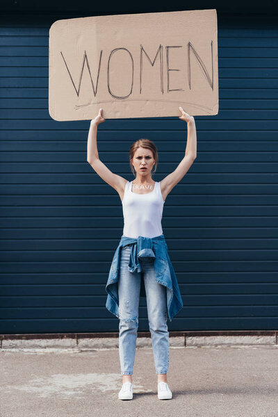 full length view of feminist holding placard with inscription women on street