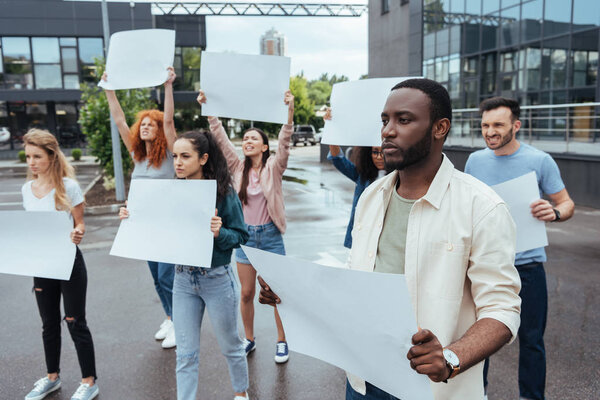 селективное внимание африканского американца, держащего пустую бабу рядом с девушками и мужчиной на улице
 