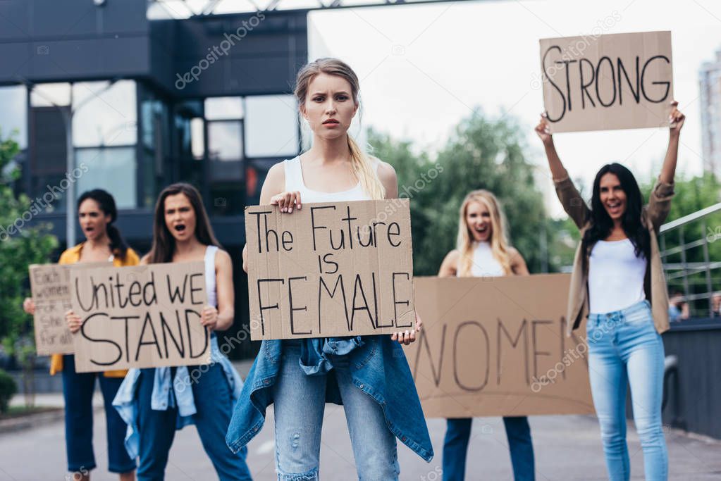 screaming multiethnic feminists holding placards with slogans on street