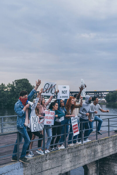 group of multicultural people standing on bridge with placards 