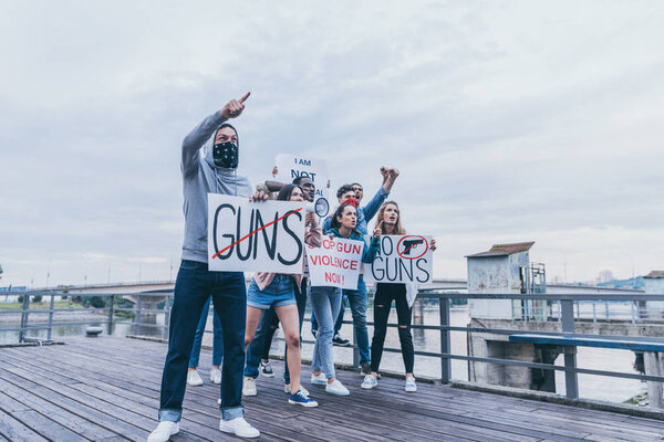 multicultural people holding placards with letters while gesturing on bridge 