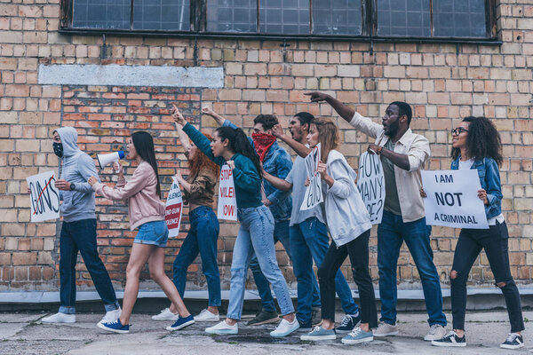 multicultural people walking near brick wall during protest 
