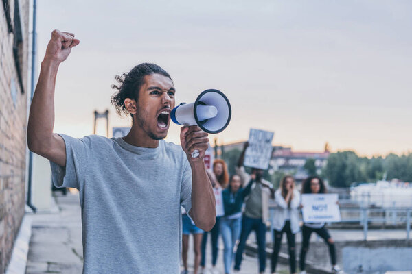 selective focus of african american man screaming while holding megaphone  