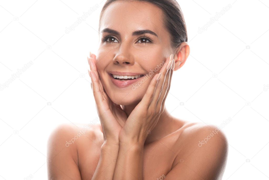 excited naked young woman touching face with hands and laughing isolated on white