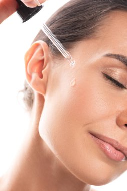 beyaz izole yüz serum uygulayan genç kadının kırpılmış görünümü
