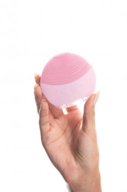 beyaz izole yüz temizleme fırçası tutan genç kadının kırpılmış görünümü