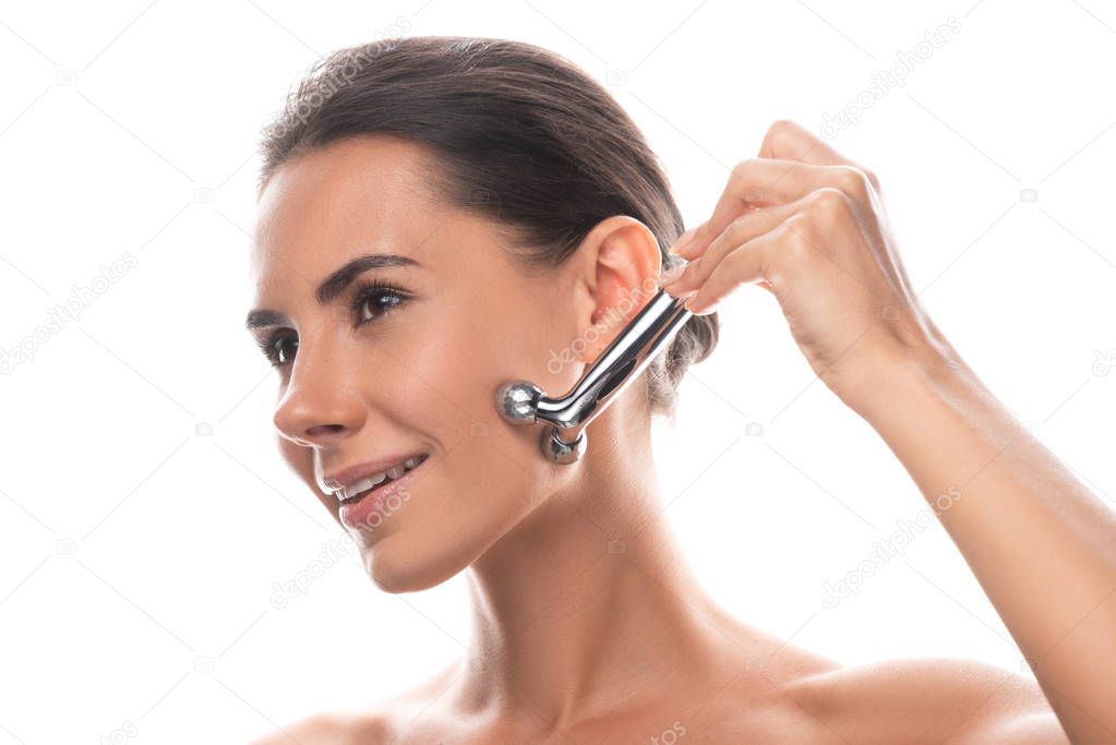 naked young woman using facial massager and smiling isolated on white