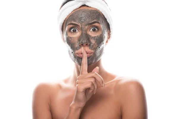 白に隔離された静かな看板を示す顔に粘土マスクを持つ化粧品のヘアバンドで驚いたヌード若い女性の正面図 — ストック写真