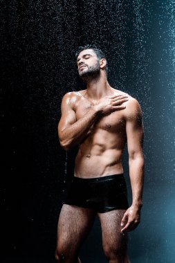 gömleksiz ve ıslak adam siyah yağmur damlaları altında ayakta 