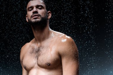 gömleksiz seksi adam siyah yağmurluk altında kamera bakıyor 