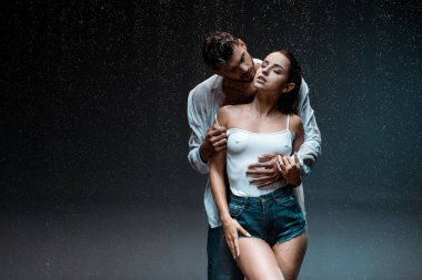 siyah yağmur damlaları altında kapalı gözleri ile seksi ve ıslak kız arkadaşı ile ayakta yakışıklı adam 