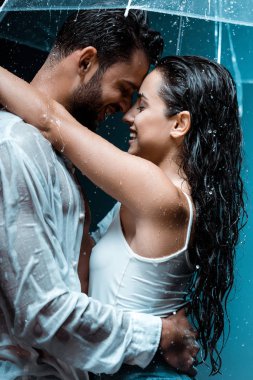 siyah yağmur damlaları altında yakışıklı erkek arkadaşı ve şemsiye sarılma neşeli kız arkadaşı yan görünümü 