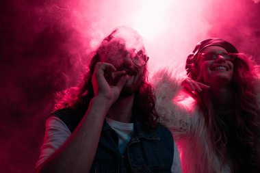 man smoking marijuana joint near smiling girl in nightclub clipart