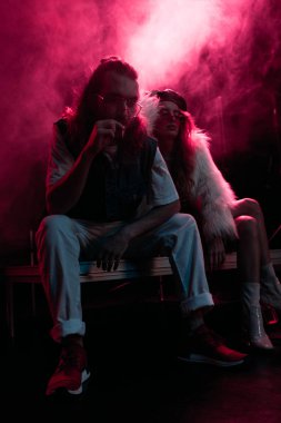 pembe duman ile gece kulübünde parti sırasında genç kadının yakınında sigara içen adam