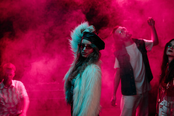 girl dancing in nightclub during rave with pink smoke 