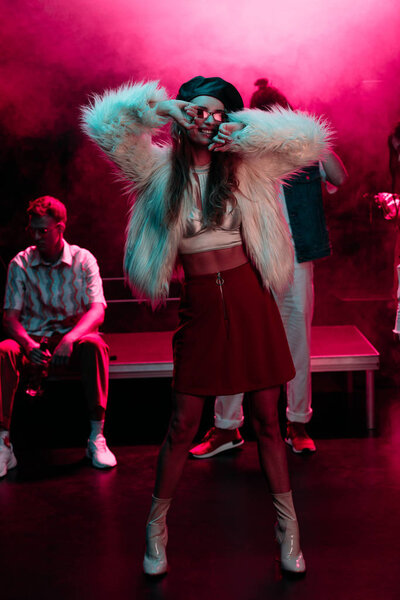 cheerful girl dancing in nightclub with pink smoke