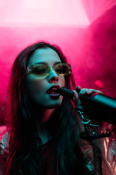 красивая девушка в солнечных очках пьет пиво в ночном клубе
 