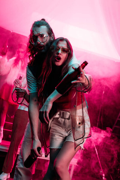 beautiful young woman and handsome man with beer in nightclub during rave