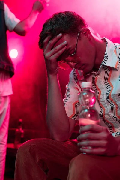 Kranker Mann Mit Kopfschmerzen Sitzt Mit Wasserflasche Nachtclub — Stockfoto