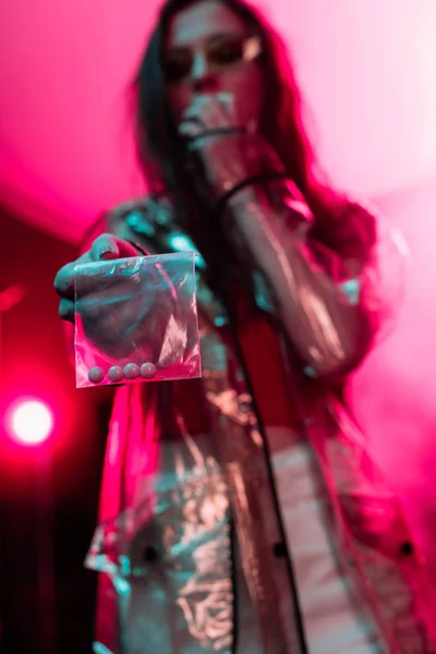 ナイトクラブで薬物を持つプラスチック製のジッパーバッグを保持している女の子 選択的な焦点 — ストック写真