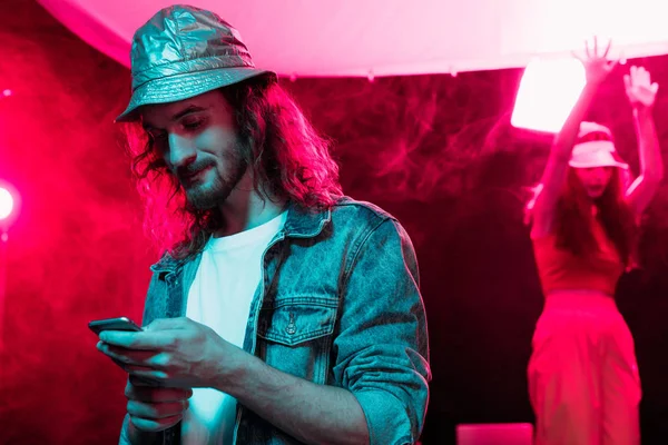 man using smartphone during rave party in nightclub