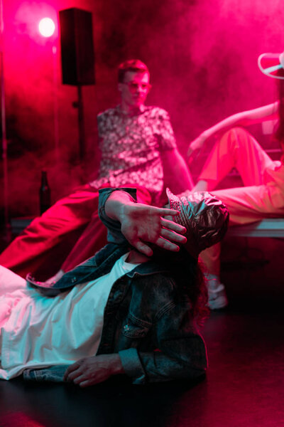selective focus of man lying on floor in nightclub and covering face