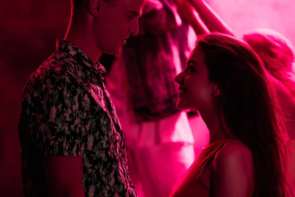 man looking at young woman during rave party in nightclub
