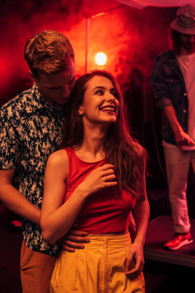 man and smiling young woman during rave party in nightclub