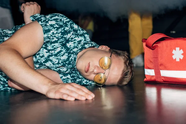 Sick Man Sunglasses Lying Floor First Aid Kit Bag Nightclub — Stock Photo, Image