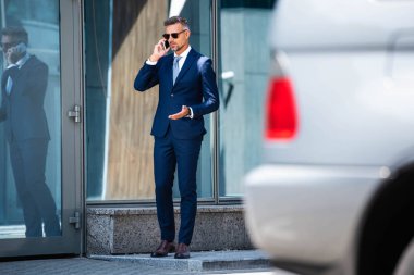 takım elbiseli yakışıklı adamın seçici odak ve gözlük akıllı telefon konuşurken 