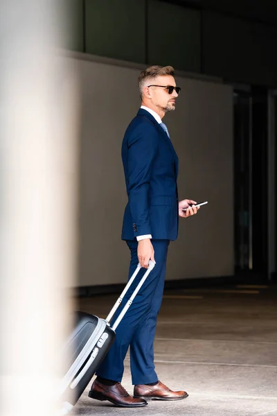 Homem Negócios Bonito Terno Óculos Segurando Mala Smartphone — Fotografia de Stock