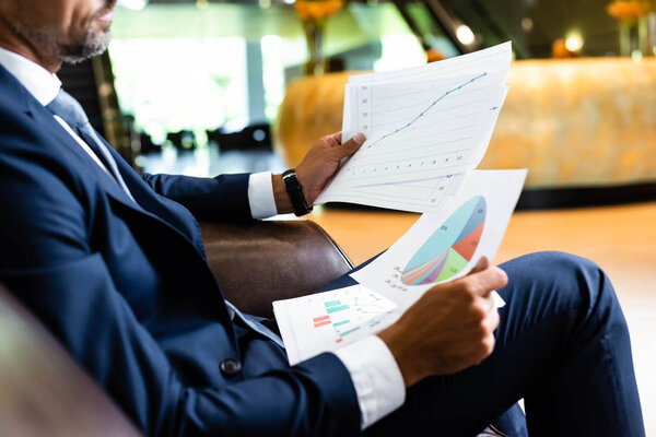 cropped view of businessman in suit holding papers in hotel 