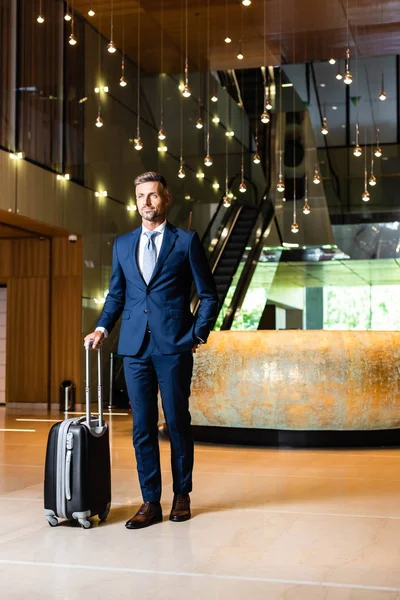 ポケットにスーツケースを持つ手でスーツを着たハンサムなビジネスマン — ストック写真