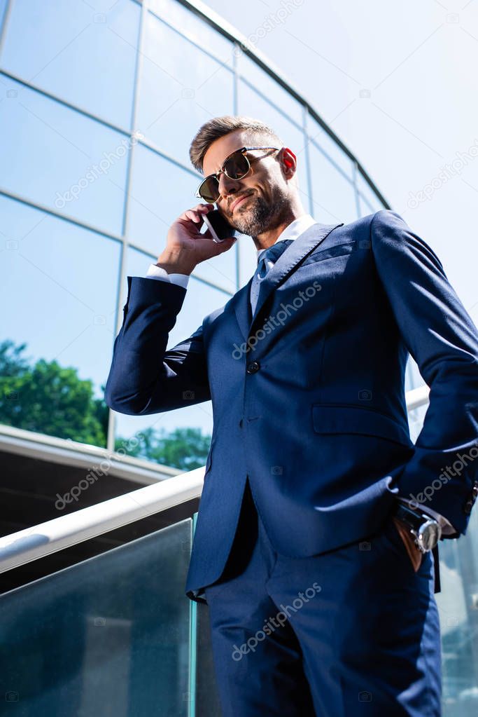 low angle view of handsome man in suit and glasses talking on smartphone 