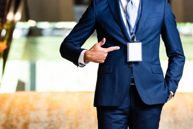cropped view of man in suit pointing with finger at badge clipart