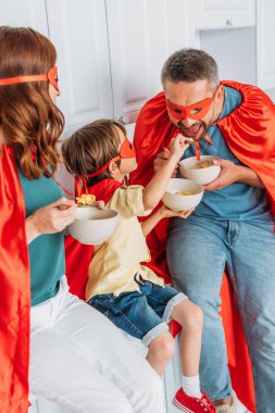mutfak tezgahında otururken kase gelen pul yeme süper kahraman kostümleri neşeli aile