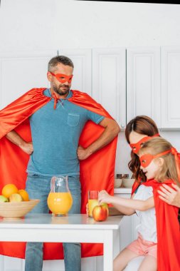 süper kahraman kostümleri aile kahvaltı yaparken, baba kalça elleri ile ayakta