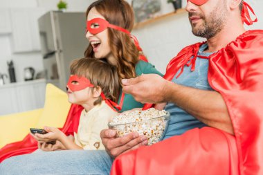 patlamış mısır yeme ve tv izlerken süper kahraman kostümleri mutlu aile