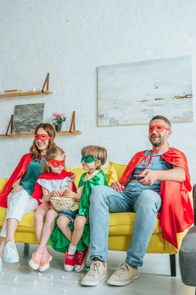 Parents Two Adorable Kids Superheroes Costumes Watching While Sitting Sofa — Stock Photo, Image