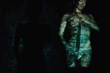 siyah ayakta vücut üzerinde gölgeler ve ışık ile soyunmuş genç kadının kırpılmış görünümü 