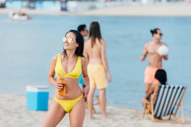 plajda dururken uzakta görünümlü mayo çekici genç kadın 