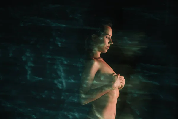黒の松の近くに立って胸を覆う裸の女の子のモーションブラー — ストック写真