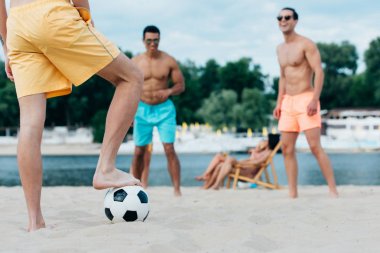 kum plajda futbol oynayan genç, yakışıklı gömleksiz erkekler